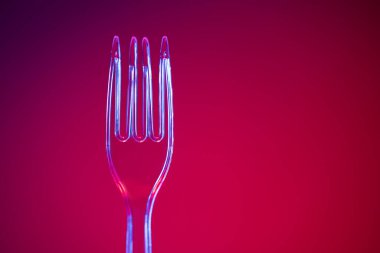 Kırmızı arkaplanda plastik şeffaf çatal