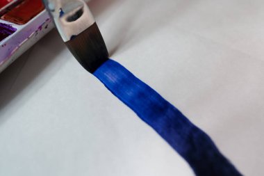 Kağıt üzerine şerit çizen bir fırça..