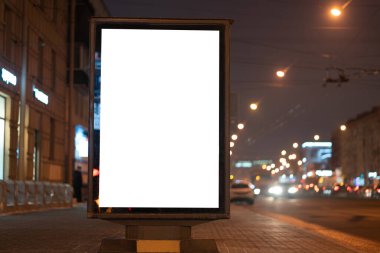 Şehirde geceleri reklam panolarının dikey ışık kutuları parlıyor, yol kenarındaki sokakta..