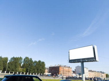 Şehrin arka planında büyük ilan panosu ve mavi gökyüzü.