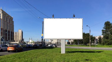 Şehirdeki büyük reklam panoları yeşil bir çimenlikte ve mavi gökyüzüne karşı.
