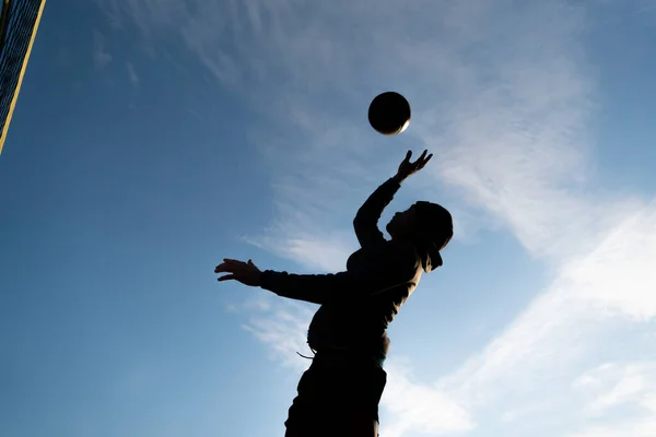 Gökyüzünde voleybol oynayan bir adamın silüeti..