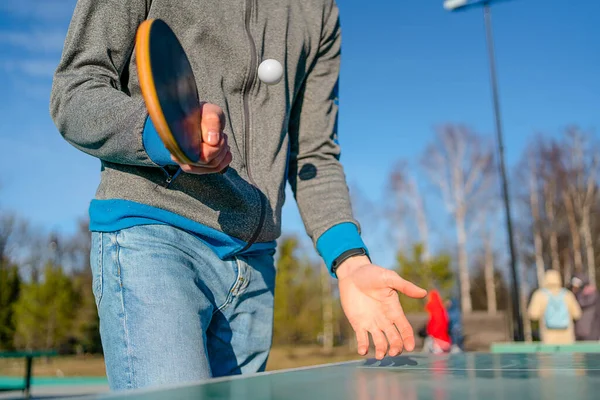 guy plays table tennis pingpong on the street. racket and ball with a tennis green table. hands in the frame and racket.