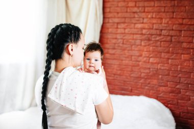 Anne kusmak için beslendikten sonra bebeği kucağına alır. kusma