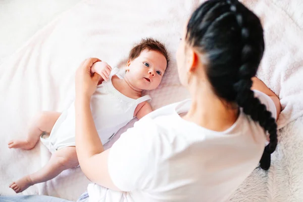 Nyfött barn med europeiskt utseende ligger med sin mor på sängen — Stockfoto