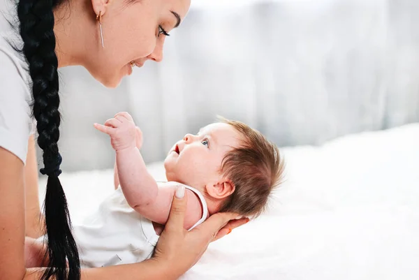 Nyfött barn med europeiskt utseende ligger med sin mor på sängen — Stockfoto