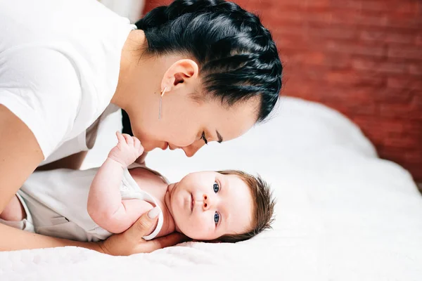 Nyfött barn med europeiskt utseende ligger med sin mor på sängen — Stockfoto