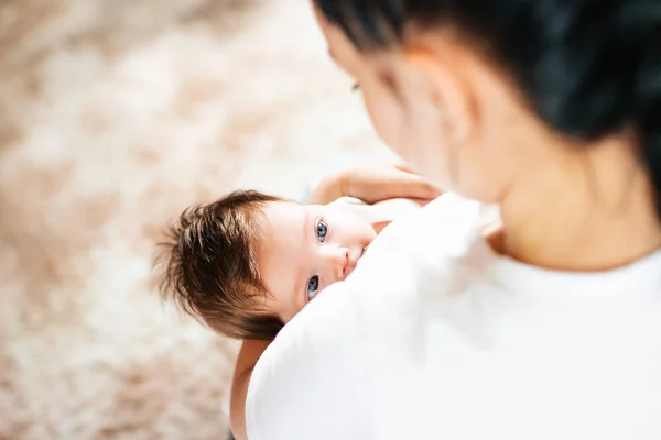 Lycklig mamma ammar sitt nyfödda barn i en vit säng — Stockfoto