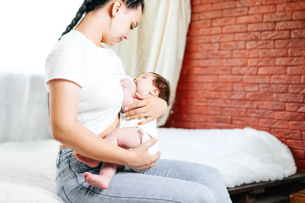 Счастливая мама кормит грудью своего новорожденного ребенка в белой кровати — стоковое фото