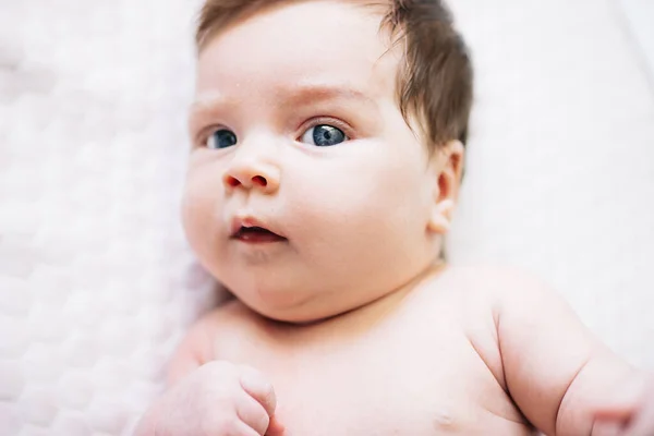 Pasgeboren baby meisje met mooie blauwe ogen liggend op het bed close-up — Stockfoto