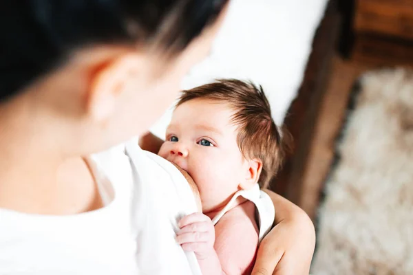 Mutlu anne yeni doğmuş bebeğini beyaz bir yatakta emziriyor..