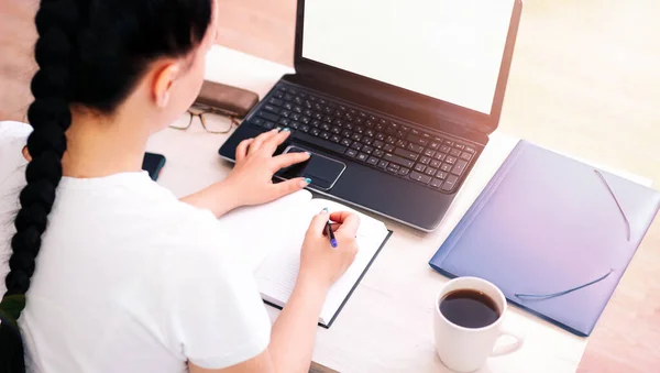 The concept of a working house is a girl at a laptop and business reports, there is a coffee mug next to it
