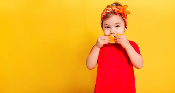 티셔츠를 아름다운 소녀와 오렌지 반다나는 배경에 오렌지 조각을 먹습니다 — 스톡 사진