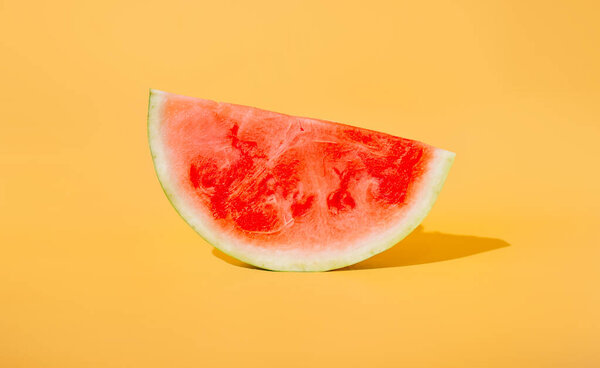 a slice of juicy appetizing red watermelon on an isolated yellow background. the concept of summer.