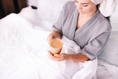 Hoş bir sabah. Neşeli, çekici genç bir kadın yatakta oturuyor ve kahve içiyor. Sabah konsepti