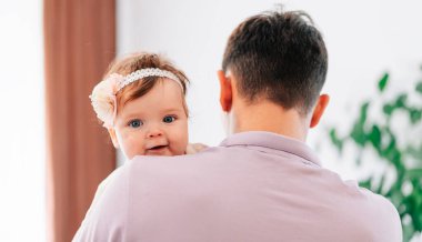 Küçük kızını kucağında tutan genç bir babanın görüntüsü. Küçük bir çocuğun portresi.