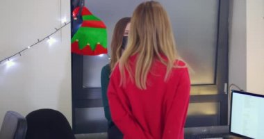 Maskeli iki kadın ofiste konuşuyor.