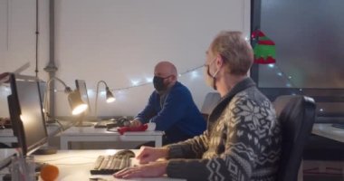 Geceleri ofiste çalışan maskeli insanlar.