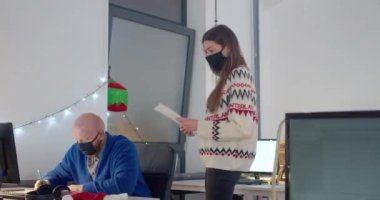 Geceleri ofiste çalışan maskeli insanlar.