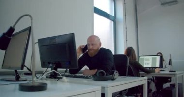 Erkek işçi ofiste telefonla konuşuyor.