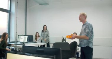 Erkek işçi ofise portakallı tabak getiriyor. 