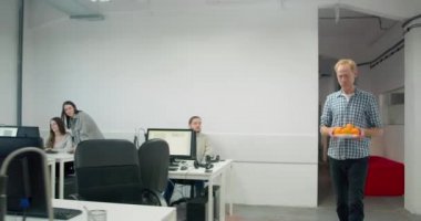 Erkek işçi ofise portakallı tabak getiriyor. 