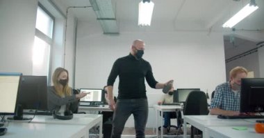 Erkek işçi ofisteki meslektaşları için dezenfektan kullanıyor. 