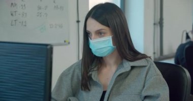 Ofiste çalışırken maske takan güzel bir bayan işçi. 