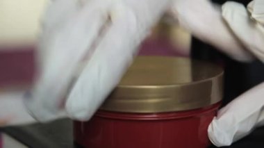 Eldivenli CU elemanı kremin içine metal nesne koyuyor, Londra, İngiltere, İngiltere