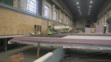 WS İnşaat işçileri İngiltere 'deki depoda vinçle hareket eden tahta kirişe rehberlik ediyorlar.