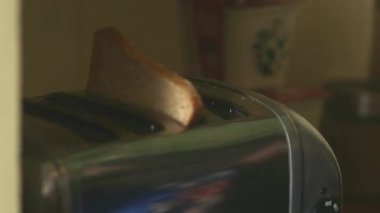 Kadın ekmek kızartma makinesine dilimlenmiş ekmek koyuyor, Londra, İngiltere, İngiltere