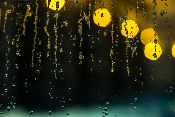Abstract background, streams of rain and snow on the glass on the background of street lighting — Stock Photo, Image