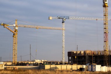Koyu mavi gökyüzüne karşı tarlada vinçleri olan bir inşaat alanı.