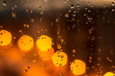 Soyut arka plan, yağmur ve kar akıntıları sokak ışıklandırmasının arka planındaki cam üzerinde