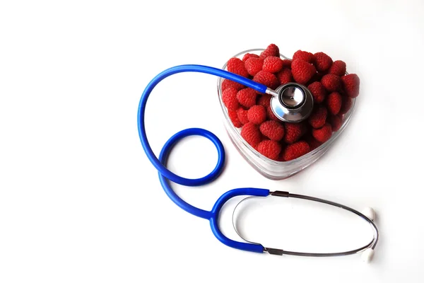 Estetoscopio azul y frambuesas rojas en forma de corazón — Foto de Stock
