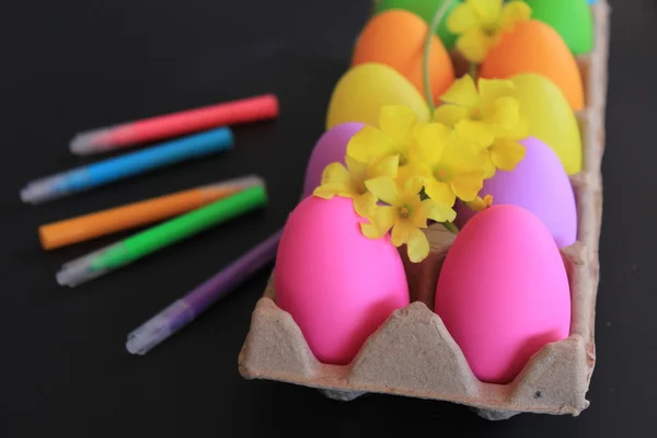 Цветные пасхальные яйца с яркими маркерами, веревкой и весенними желтыми цветами — стоковое фото