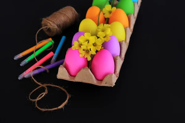 Ovos de Páscoa coloridos com marcadores coloridos, corda e flores amarelas primavera — Fotografia de Stock