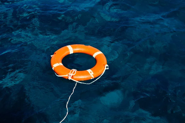 Una boya de salvamento naranja flotando en medio del océano Fotos de stock