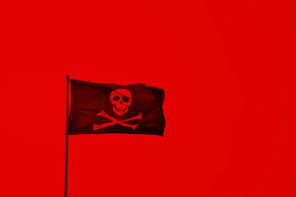 Sebuah bendera bajak laut berwarna merah dengan tengkorak dan tulang — Stok Foto