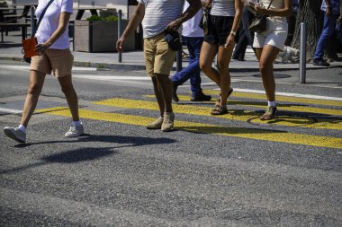 Sarı zebra üzerinde yürüyen bir grup insan, yan görüş. İnsanlar kalabalık bir şehirde yaya geçidinde. 8K çözünürlüğü. Şehir hayatı kavramları.