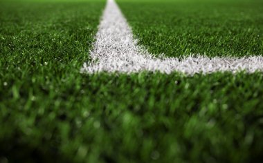 Yeşil sentetik çimen spor sahasının fotoğrafı. Yukarıdan beyaz çizgili. 8K Çözünürlük. Arkaplan olarak kullanmak için harika.