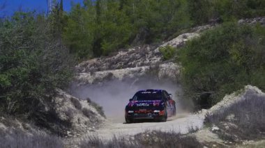 LARNACA, CYPRUS - 14 Aralık 2025: Kıbrıs Rum Kesimi, Kornos bölgesinde toplandı. Tozlu bir yolda yarışan arabanın yavaş çekim görüntüleri..