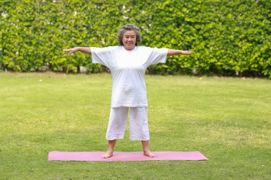 Asyalı yaşlı kadın bahçede pilates yapıyor..