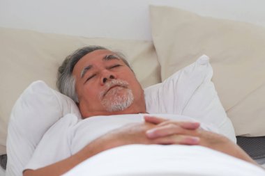 Asyalı yaşlı adam uyuyor ve tatlı rüyalar görüyor..