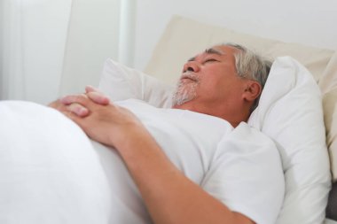 Asyalı yaşlı adam uyuyor ve tatlı rüyalar görüyor..