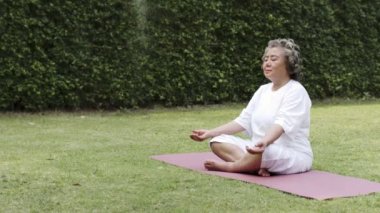 Meditasyon yapan Asyalı yaşlı kadın..