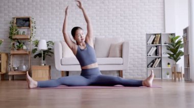 Asyalı kadın yogası ön tarafta oturarak yoga minderinde poz veriyor. 