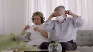 Bazı Asyalı yaşlılar oturma odasında maske takıyor..