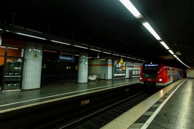 Münih 'in merkezindeki Marienplatz' daki tren istasyonu ilkbahar Coronavirus salgını sırasında kırmızı bir S-Bahn treni oraya varıyor..