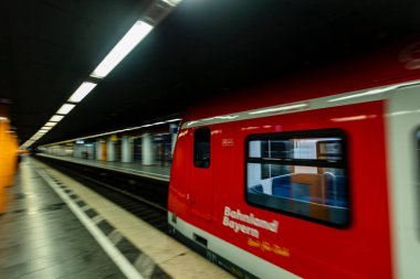 Münih 'in merkezindeki Marienplatz' daki tren istasyonu ilkbahar Coronavirus salgını sırasında kırmızı bir S-Bahn treni oraya varıyor..